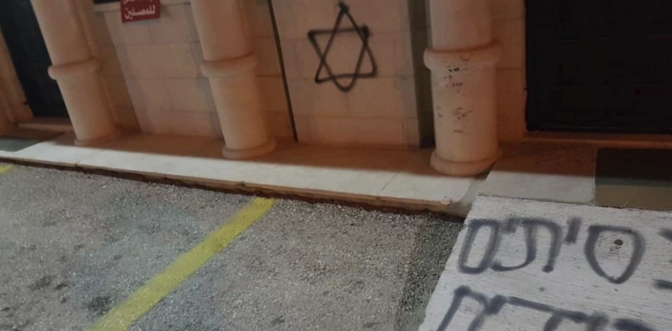 Settlers take slogans on the walls of a mosque in Deir Dabwan
